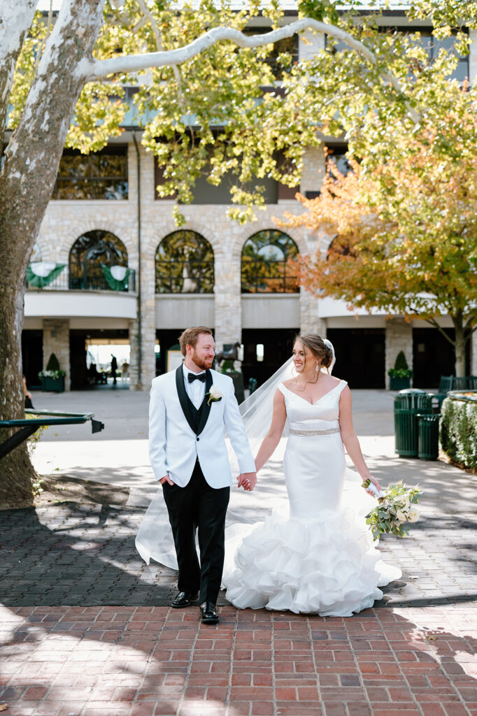 Outdoor wedding venues in Lexington KY – couple at Keeneland walking through courtyard and glowing light.