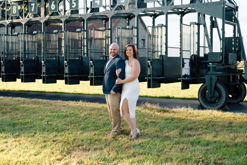 A couple facing the camera and smiling together near traditional gates at Keeneland wedding venue