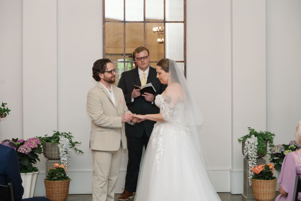 Bride and groom exchanging rings during an indoor ceremony at Hazelnut Farm Events in Louisville, KY. 