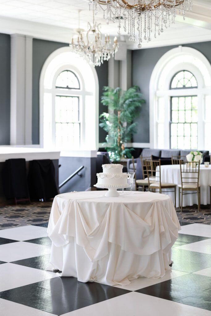 Classic wedding cake displayed beneath crystal chandeliers at The Olmsted Louisville, KY wedding reception.