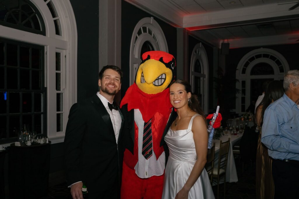 Bride and groom posing with the Louisville Cardinals mascot during their fun The Olmsted Louisville wedding reception.