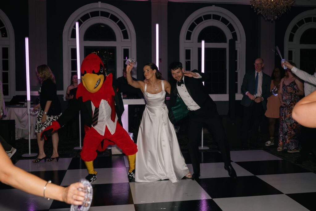 Bride and groom celebrating on the dance floor with a surprise Cardinal mascot appearance at The Olmsted Louisville wedding reception.