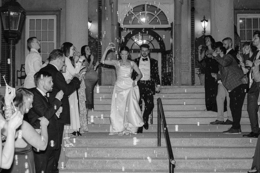 Bride and groom making their grand bubble exit down the steps of The Olmsted Louisville.