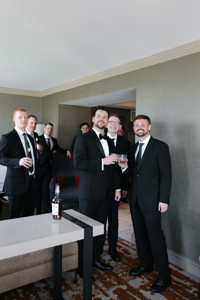 Groom celebrating with his groomsmen while getting ready before the wedding at The Olmsted.