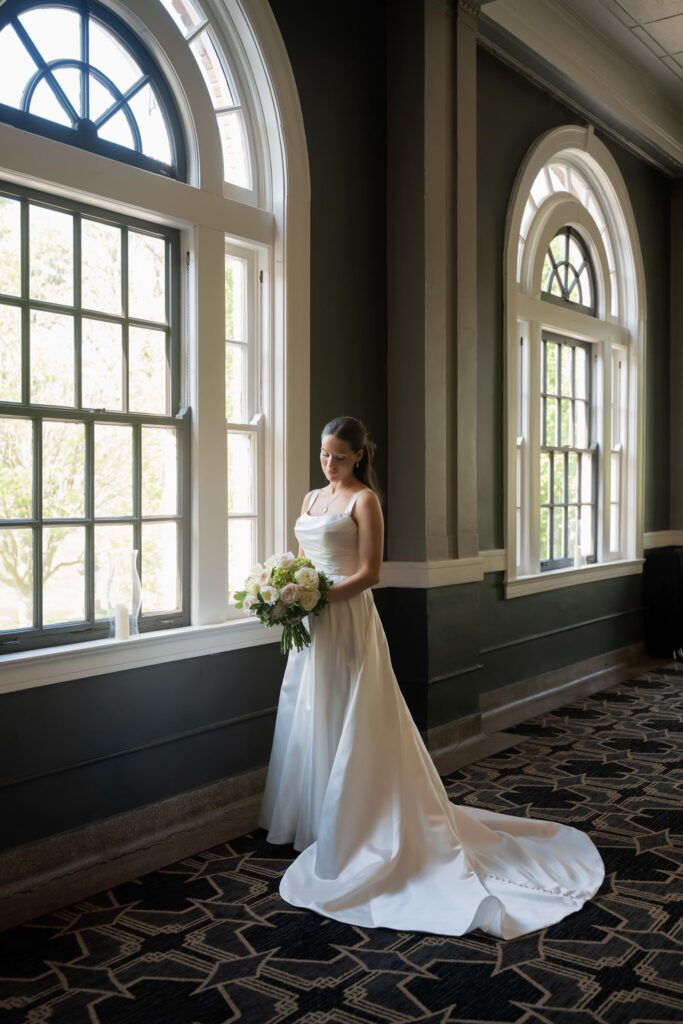 Bride holding her bouquet by the arched windows inside The Olmsted wedding venue in Louisville.