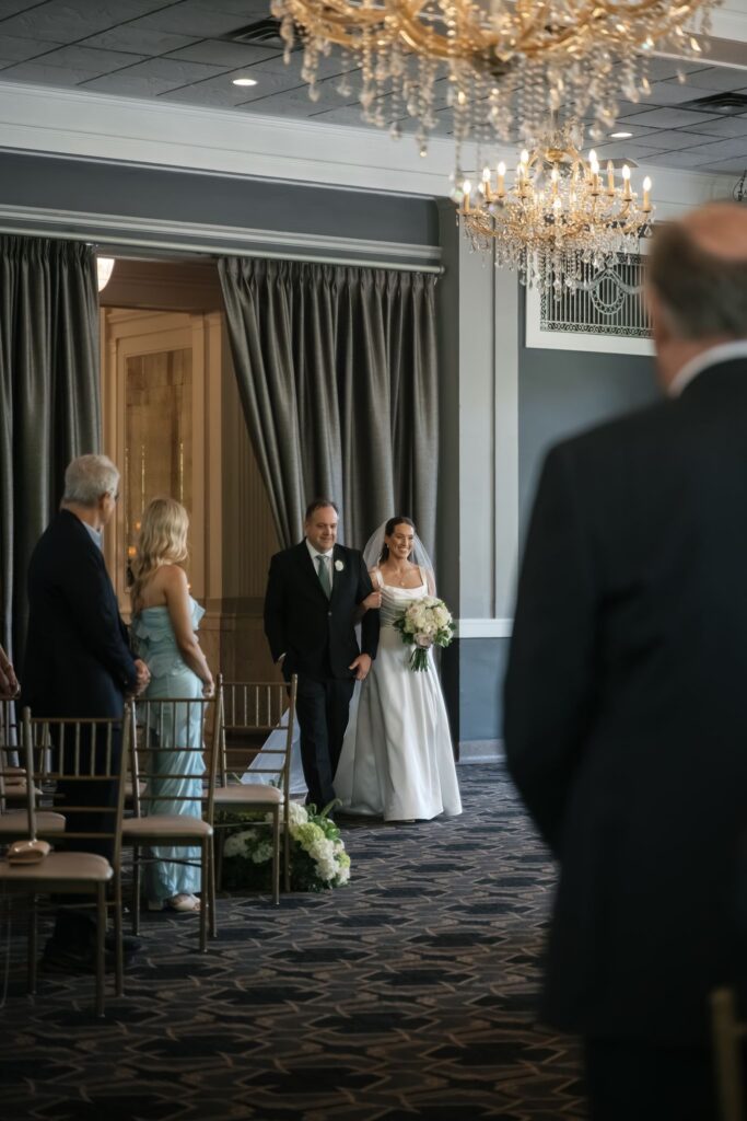 Bride walking down the aisle with her father during a wedding ceremony at The Olmsted.
