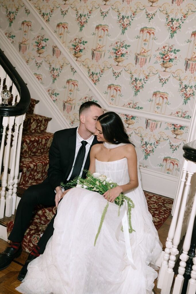Groom kissing bride's cheek on the staircase at Whitehall, an outdoor wedding venue in Louisville, KY.