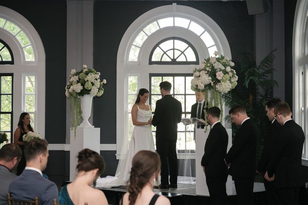 Bride putting the ring on groom at ceremony in an indoor outdoor wedding venue in Louisville, KY, called Olmstead.