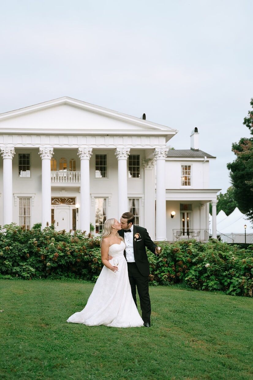 Bride and groom kissing in front of a historic building at an outdoor wedding in Louisville.