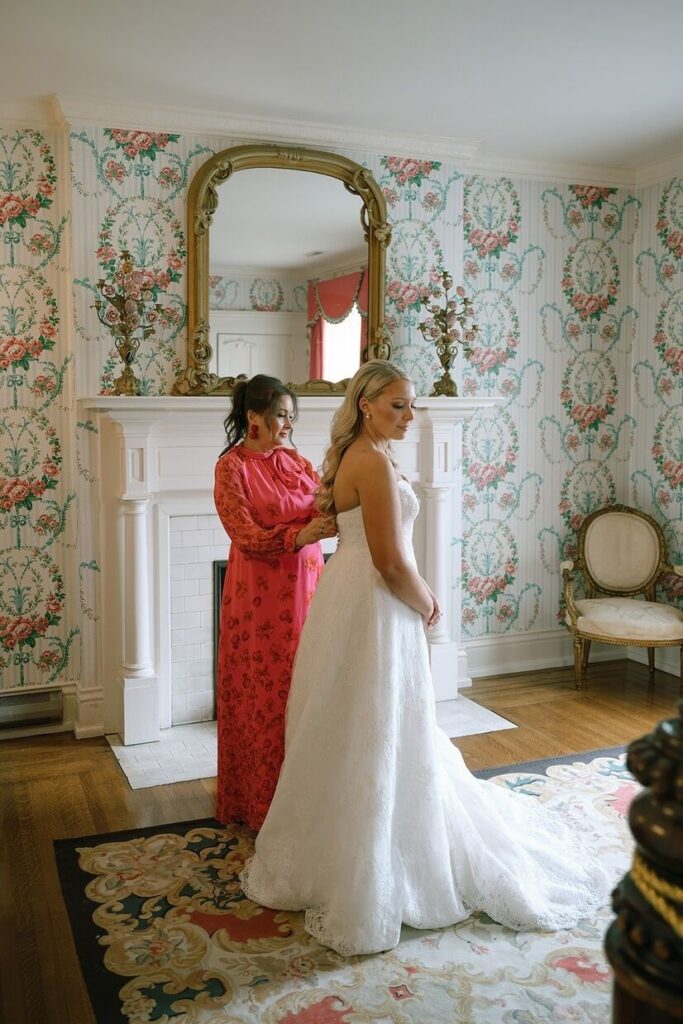 Bride putting her dress on with her mom at Whitehall wedding venue. 